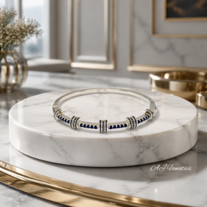 Blue Mirage 925 Silver Sapphire Blue Bangle Bracelet with rows of deep blue stones and detailed silver stations, displayed on a round white marble stand in a luxe interior setting.