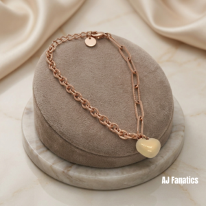 Heart Charm Bracelet in rose gold-plated stainless steel, featuring a glossy beige heart charm and mixed links, displayed on a classic jewellery cushion.