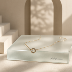 Roma Vitae gold stainless steel necklace featuring a circular Roman numeral pendant linked with a crystal-studded ring on a delicate gold chain.