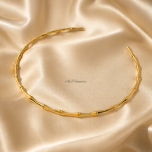 Forest Whisper Stainless Steel Gold Necklace in a sleek, open choker design with bamboo-inspired segments, displayed against a light beige silk background.