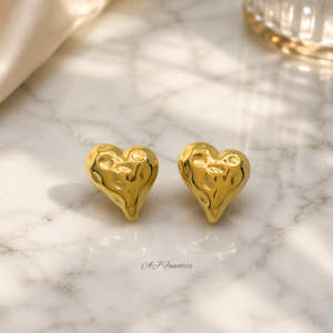 Golden irregular heart-shaped stainless steel earrings on a marble table background, with a soft molten texture that reflects light.