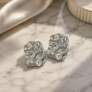 Wanderlust Wave Stainless Steel Silver Earrings on a white background, shown as a pair of crinkled, rectangular silver studs angled slightly apart to showcase their sculptural shine.